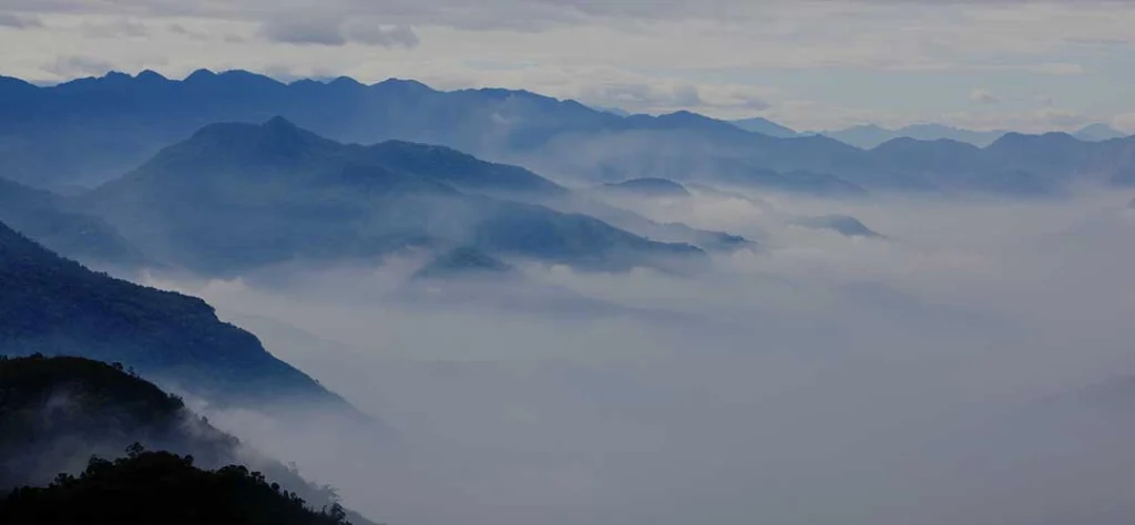 A mountain range covered in clouds with mountains in the background.