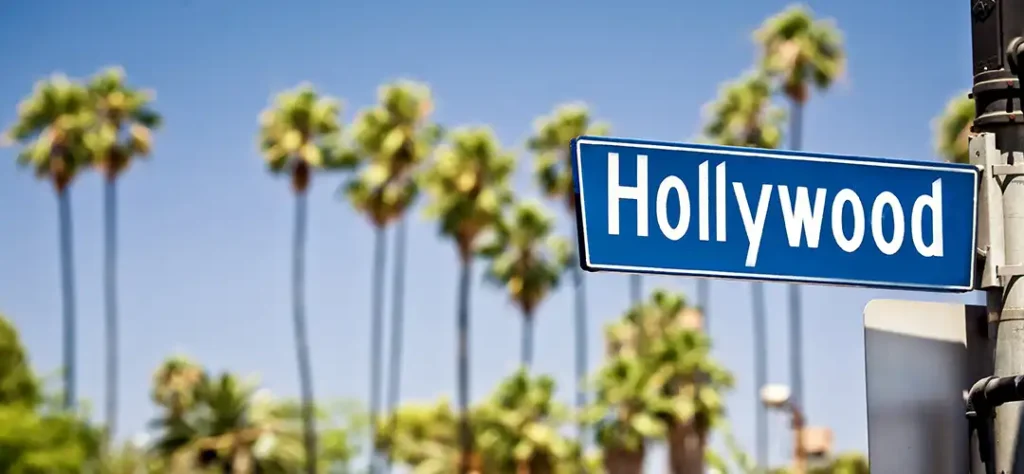 Hollywood street sign with palm trees in the background.